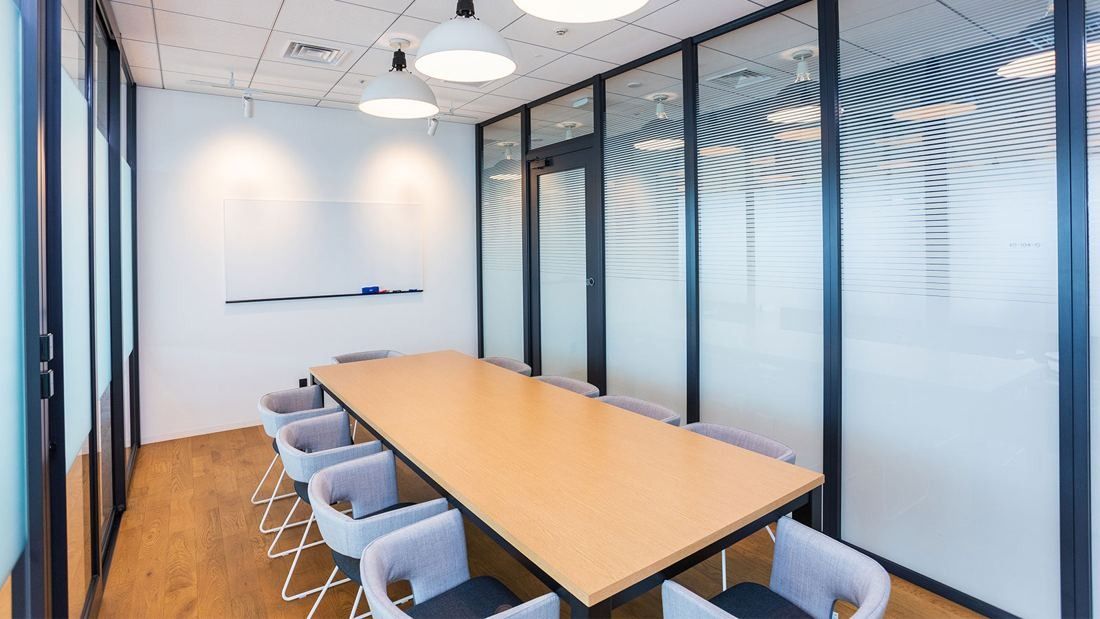 DeNA: Small glass-walled meeting room with a wooden table and white chairs