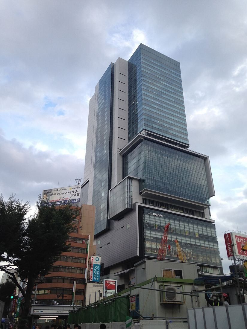 Tall glass skyscraper with stacked sections above a busy street