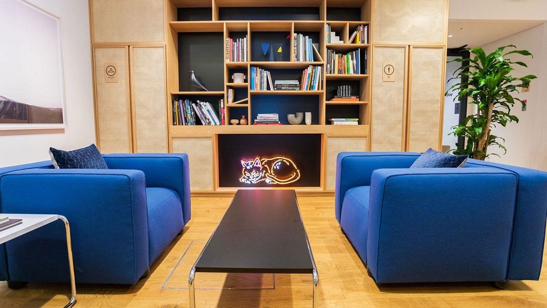 DeNA: Two blue armchairs facing a low table in front of a bookshelf