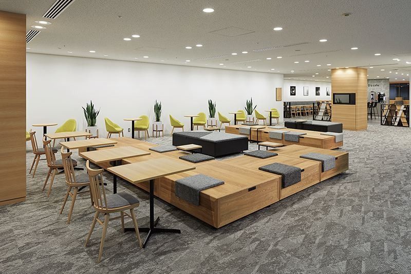 Denso: Lounge with low wooden platforms, grey cushions, wooden chairs and yellow armchairs