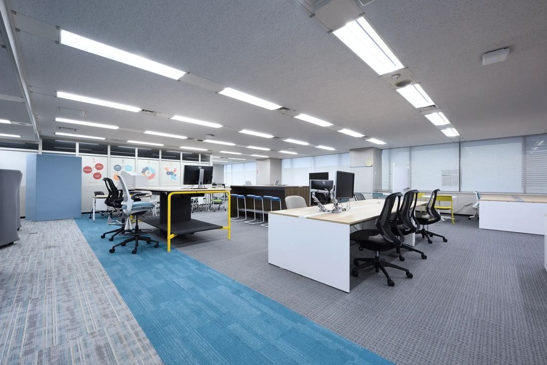 Denso: Open office floor with white desks, mesh chairs and a blue carpet path between work areas
