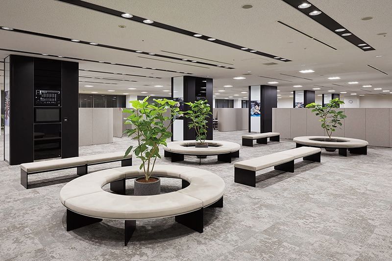 Denso: Waiting area with round white benches around potted trees and black columns