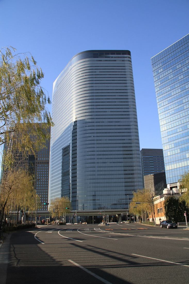 Dentsu: A tall glass tower with a curved edge at the end of a wide, empty street