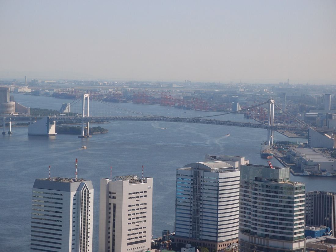 Dentsu: Elevated view of a suspension bridge over the bay behind waterfront towers