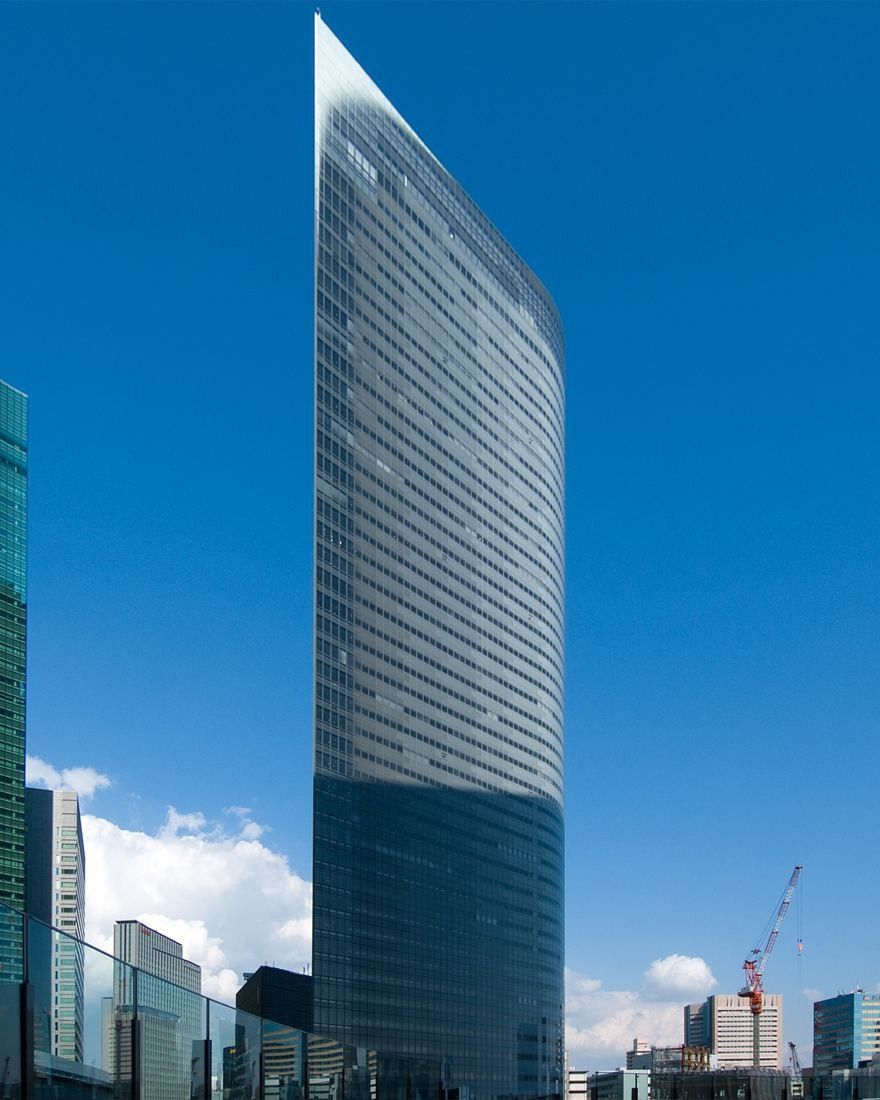 Dentsu: Glass tower with a darker base rising above surrounding buildings