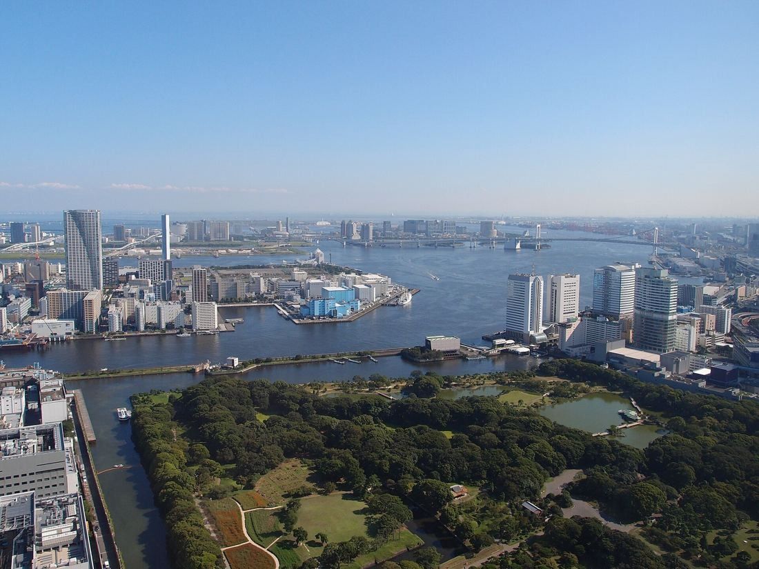 Dentsu: High view over a large green garden, a river mouth and the bay