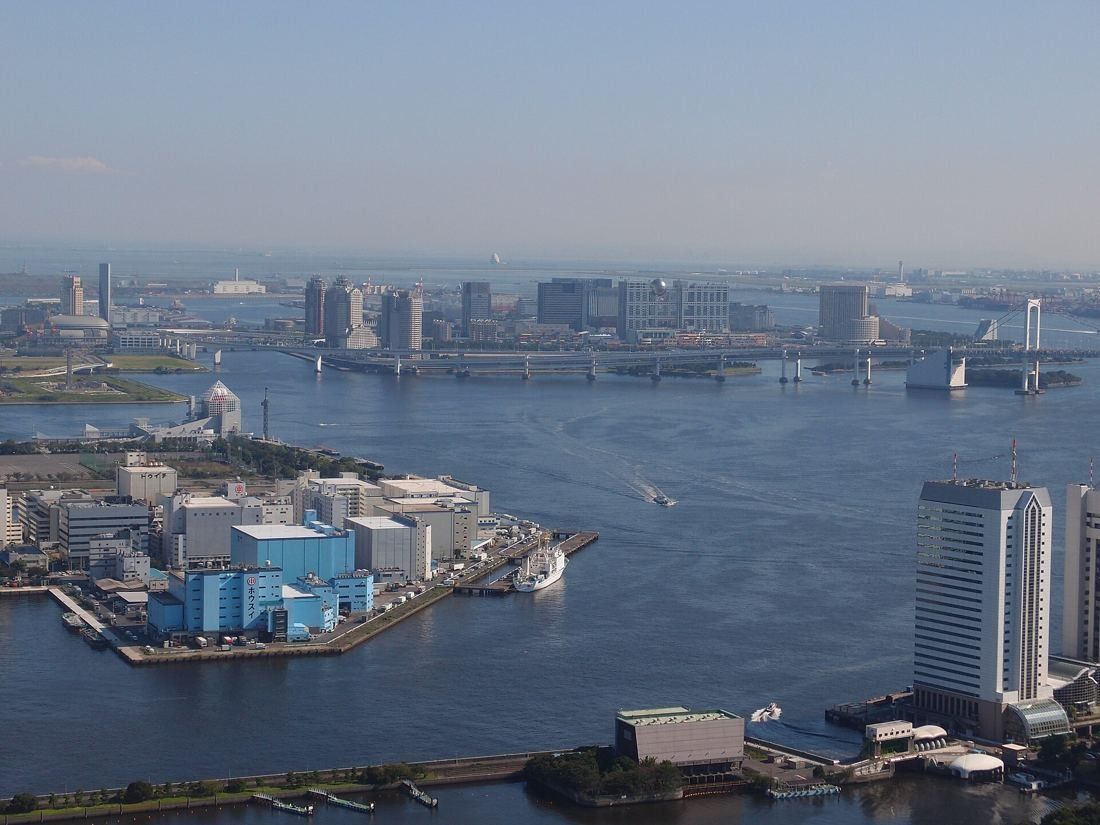 Dentsu: High view over Tokyo Bay, waterfront warehouses and a distant bridge