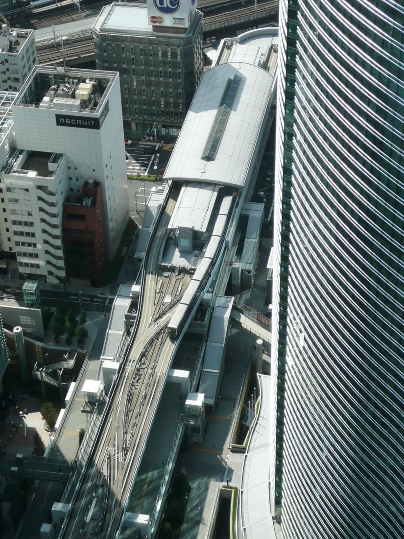 Dentsu: Looking down the tower's glass wall onto an elevated transit station