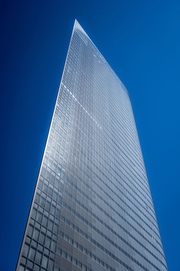 Dentsu: The thin, sharp edge of a glass tower against a blue sky