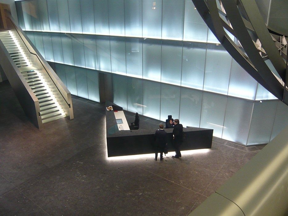 Deutsche Bank: Black reception desk in a lobby with glowing glass walls and a staircase