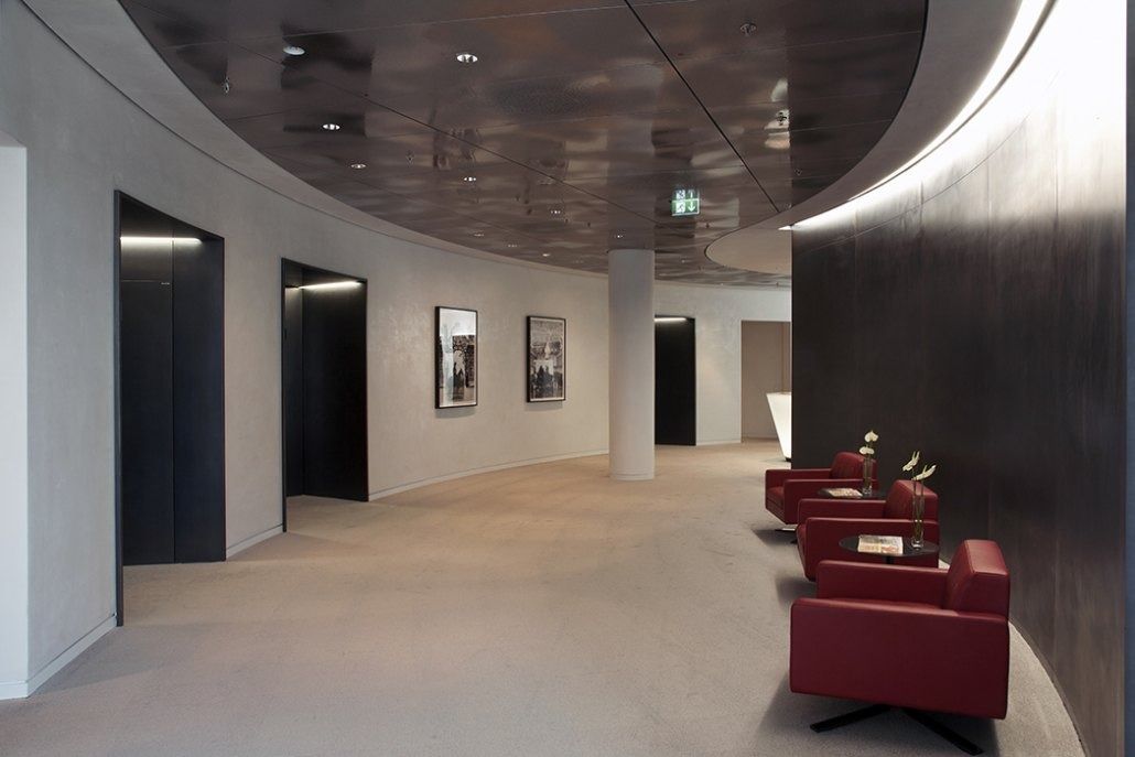 Deutsche Bank: Curved corridor with lift doors, framed pictures and red armchairs