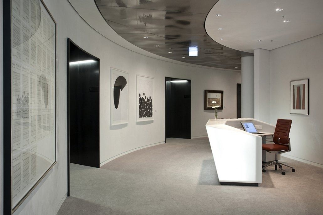 Deutsche Bank: Curved reception area with white desk, framed artworks and dark wall panels