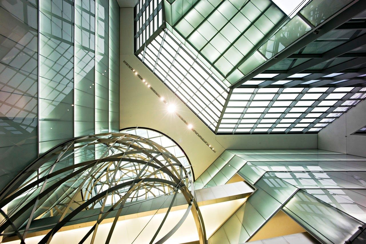 Deutsche Bank: Curved steel bands under an angular glass roof in a bright entrance hall