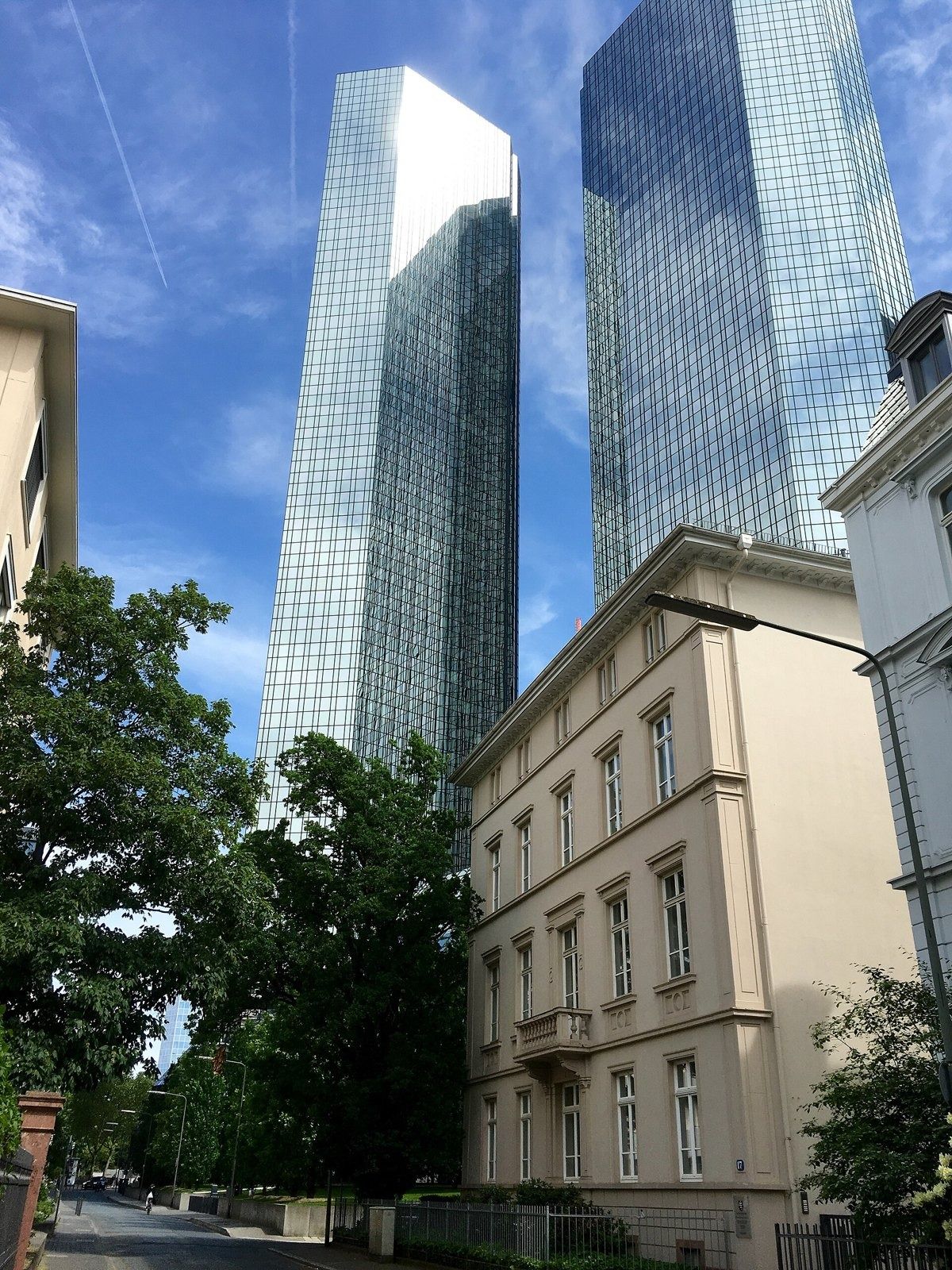 Deutsche Bank: Glass towers rising behind an older stone building and trees