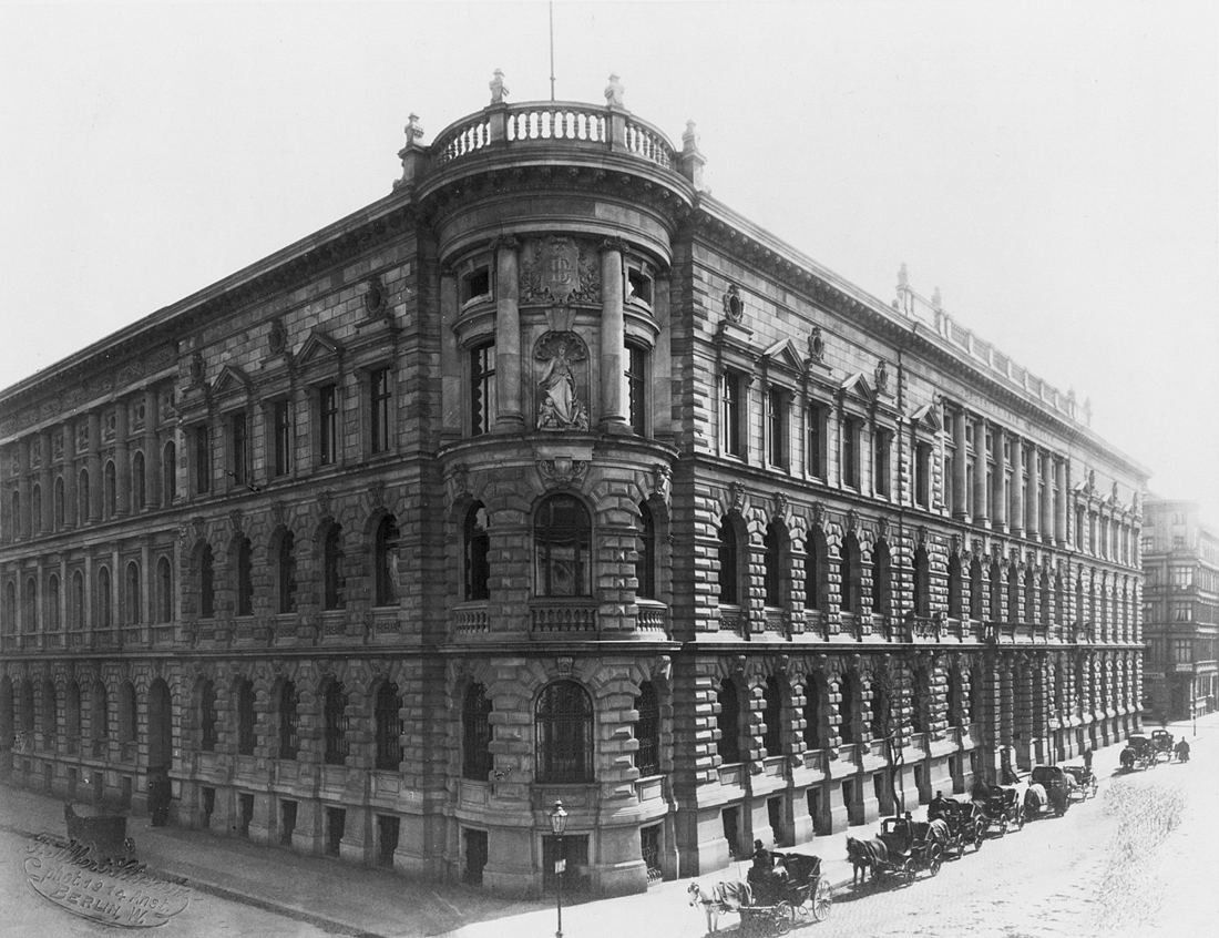 Black-and-white photo of an ornate stone bank building on a street corner