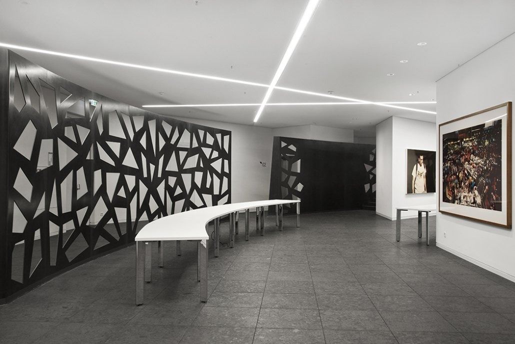 Deutsche Bank: Open space with black patterned screen wall, curved white tables and framed photographs
