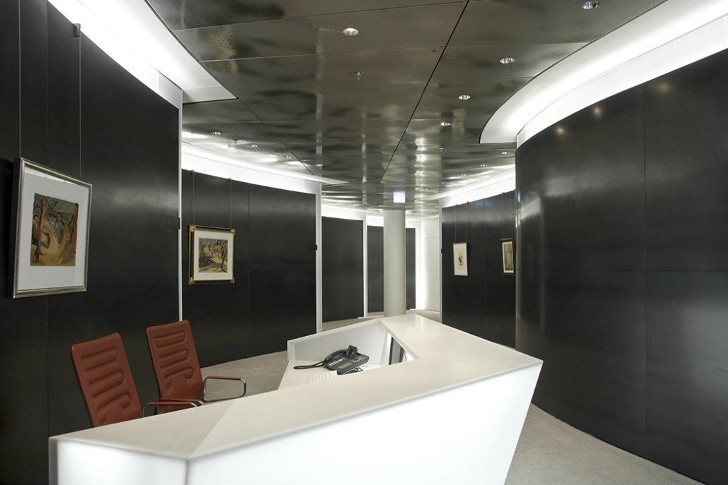 Deutsche Bank: Reception desk with red chairs in a curved corridor with framed art