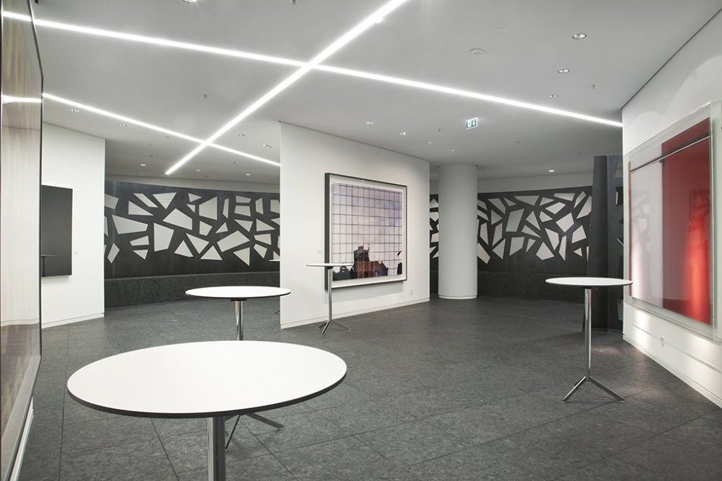 Deutsche Bank: Room with round white tables, black lattice screen and large framed photographs