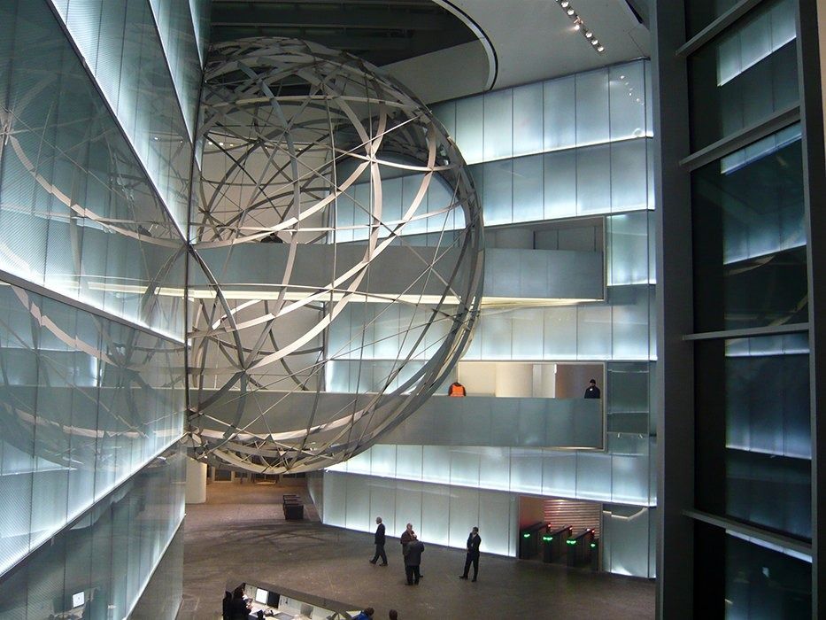 Deutsche Bank: Tall atrium lit by backlit glass walls with a metal sphere hanging in the middle