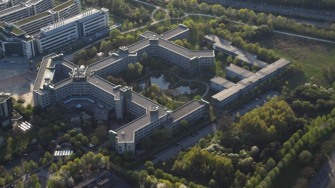 Aerial view of a large office complex with several wings around courtyards and trees
