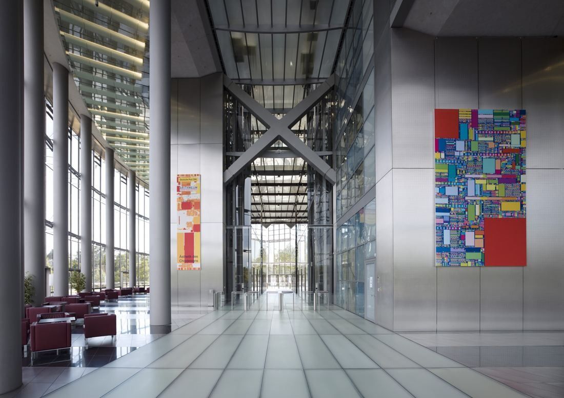 DHL Group: Long glass lobby with steel cross-bracing, red chairs and a colourful artwork