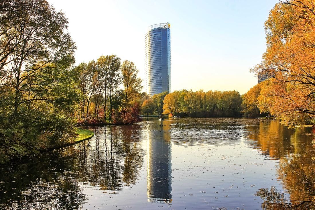 DHL Group: Tower reflected in a park lake with autumn trees