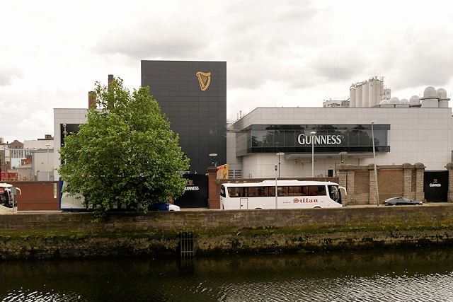 Brewery buildings with a large harp sign and a GUINNESS-branded building across a river