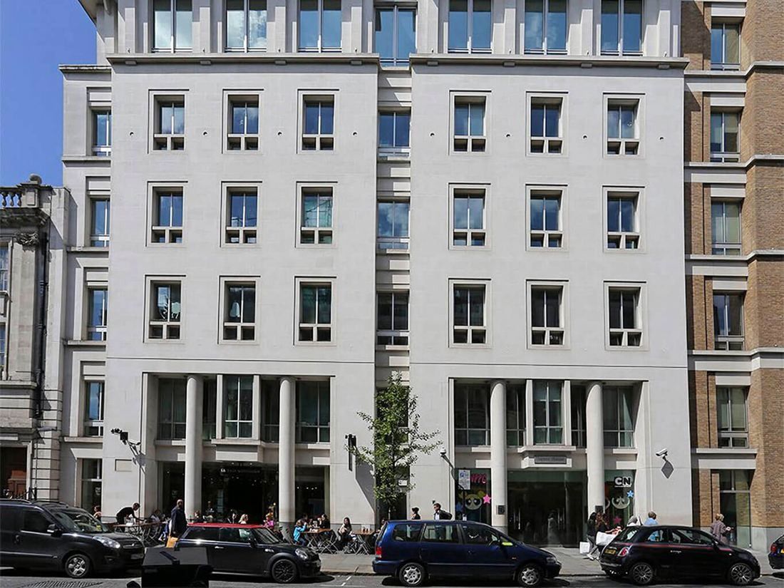 Diageo: Front elevation of a pale stone office building with tall columns at street level and parked cars