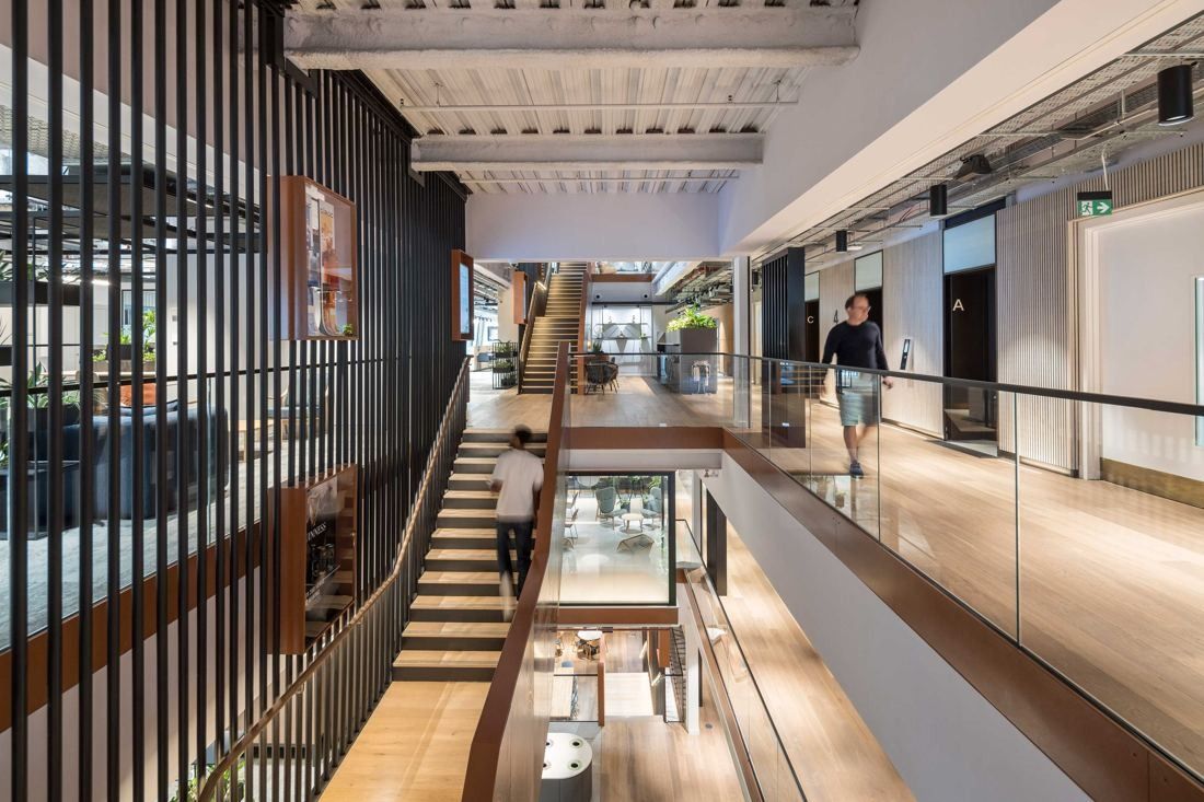Diageo: Multi-level atrium with a timber staircase, black vertical slats and glass balustrades