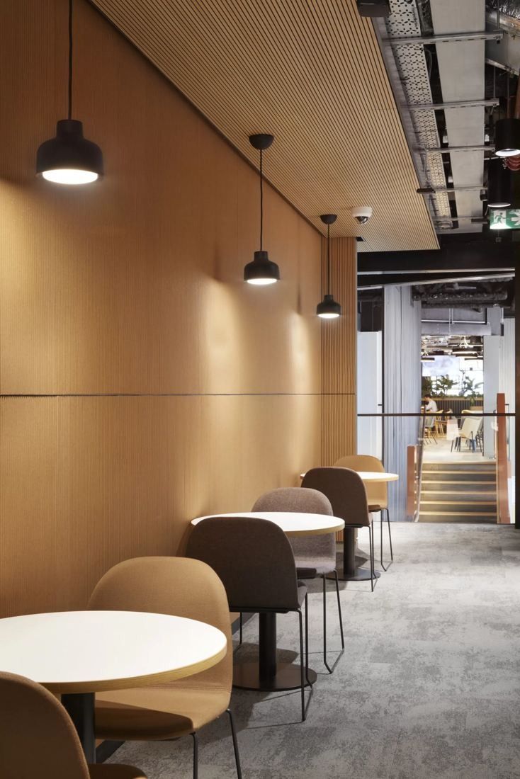 Diageo: Row of round tables and chairs along a timber-lined wall with pendant lamps