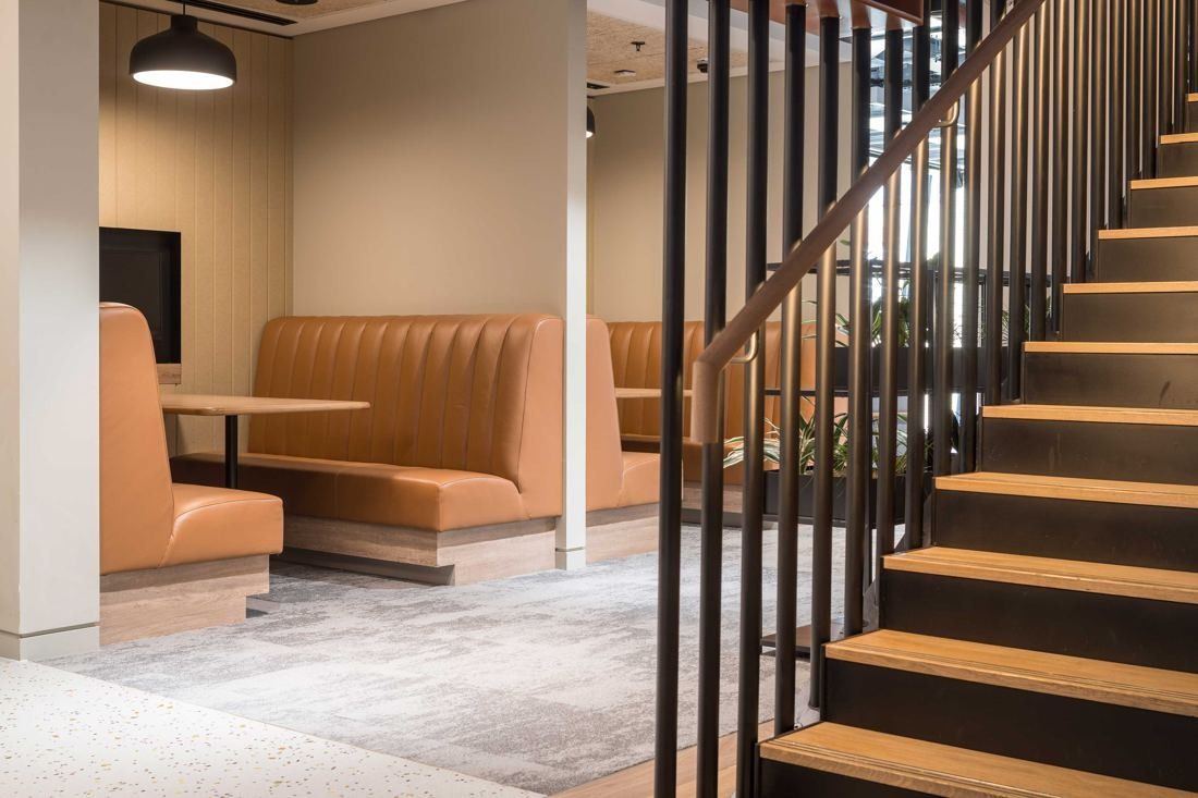 Diageo: Tan leather booth seating next to a timber staircase with black balusters