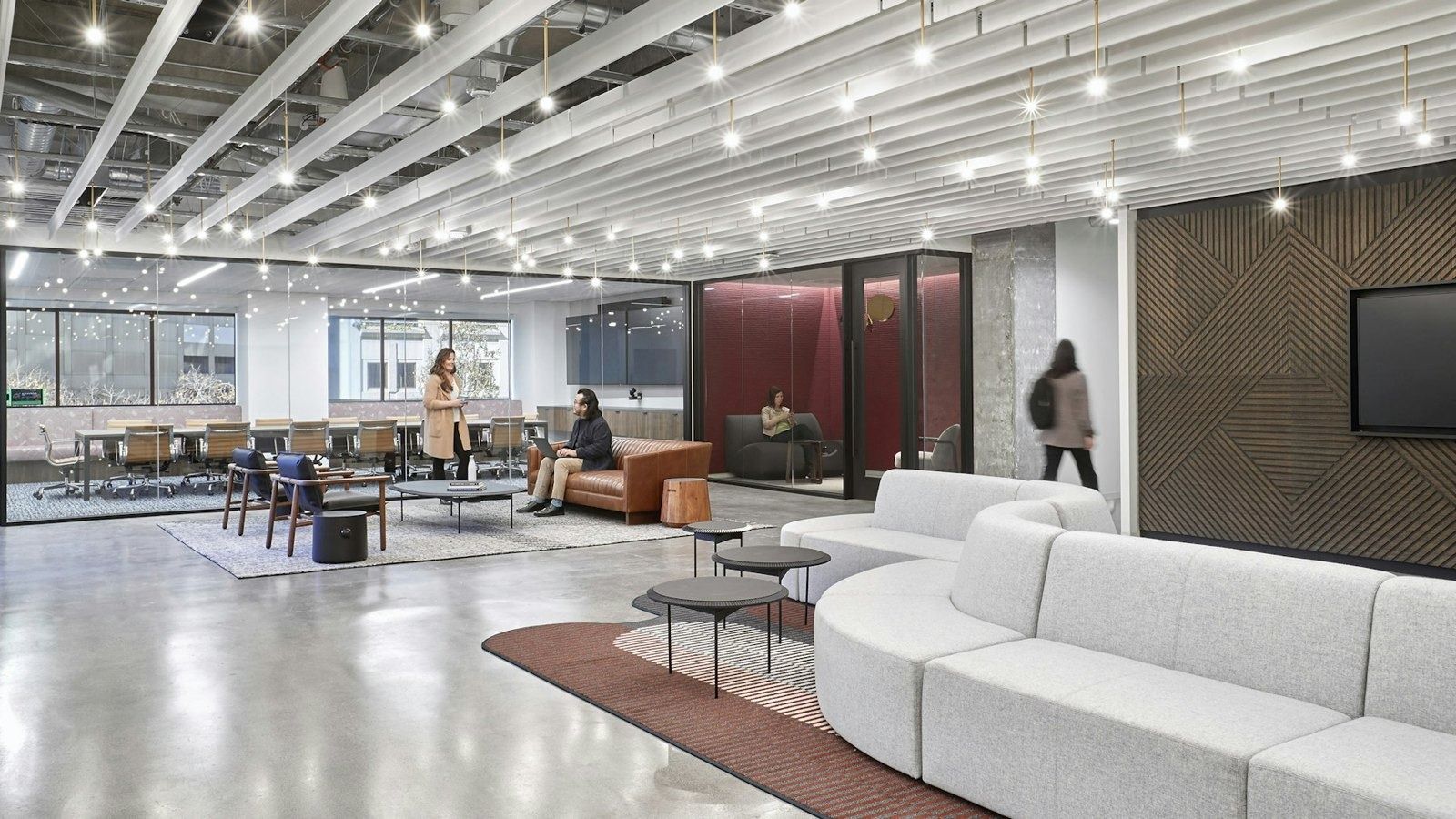 Open lounge with a long curved white sofa and a dotted lighting grid
