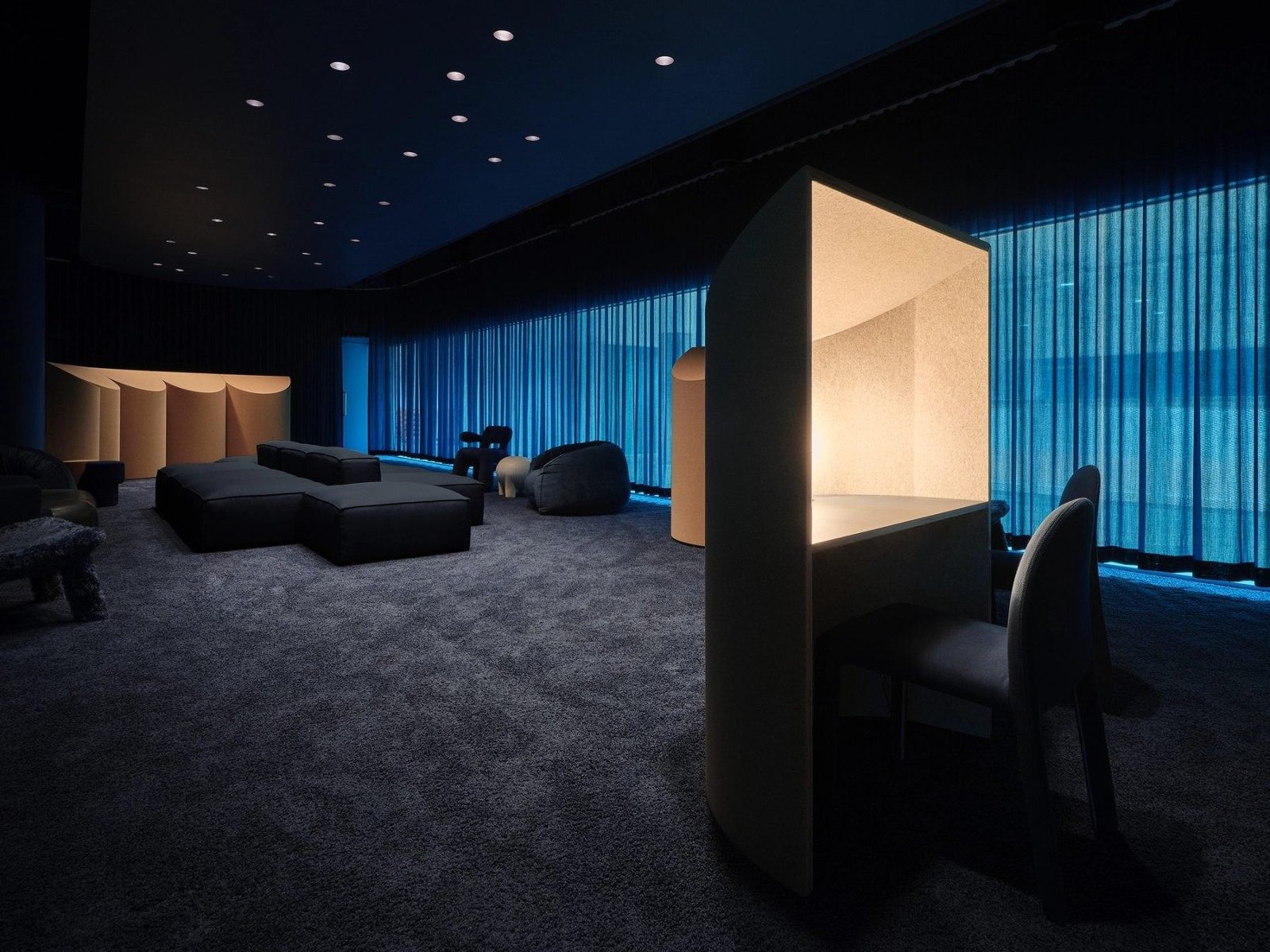 Dropbox: A dark lounge lit in blue with a lit study booth