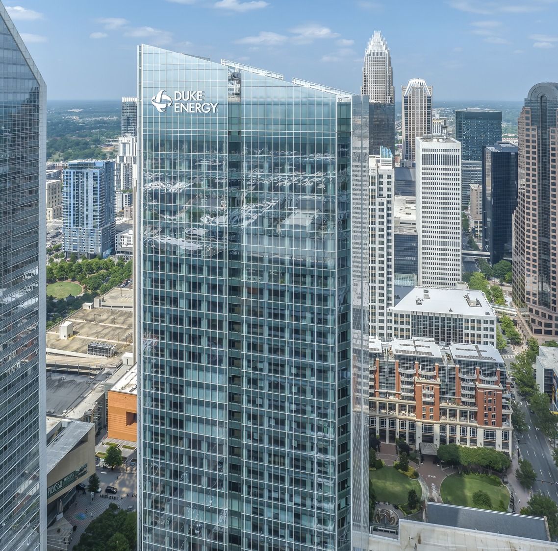 Glass tower with the Duke Energy name at the top above Uptown Charlotte