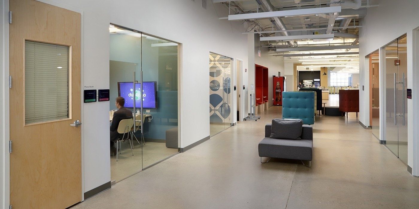 Duolingo: Corridor lined with glass-walled rooms leading to a café area