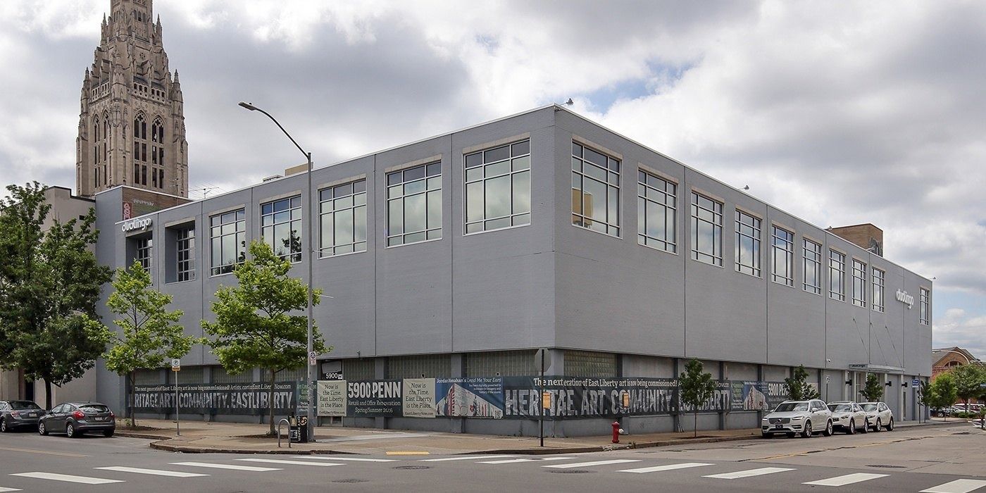 Duolingo: Gray two-story corner building with rows of windows and a church spire behind