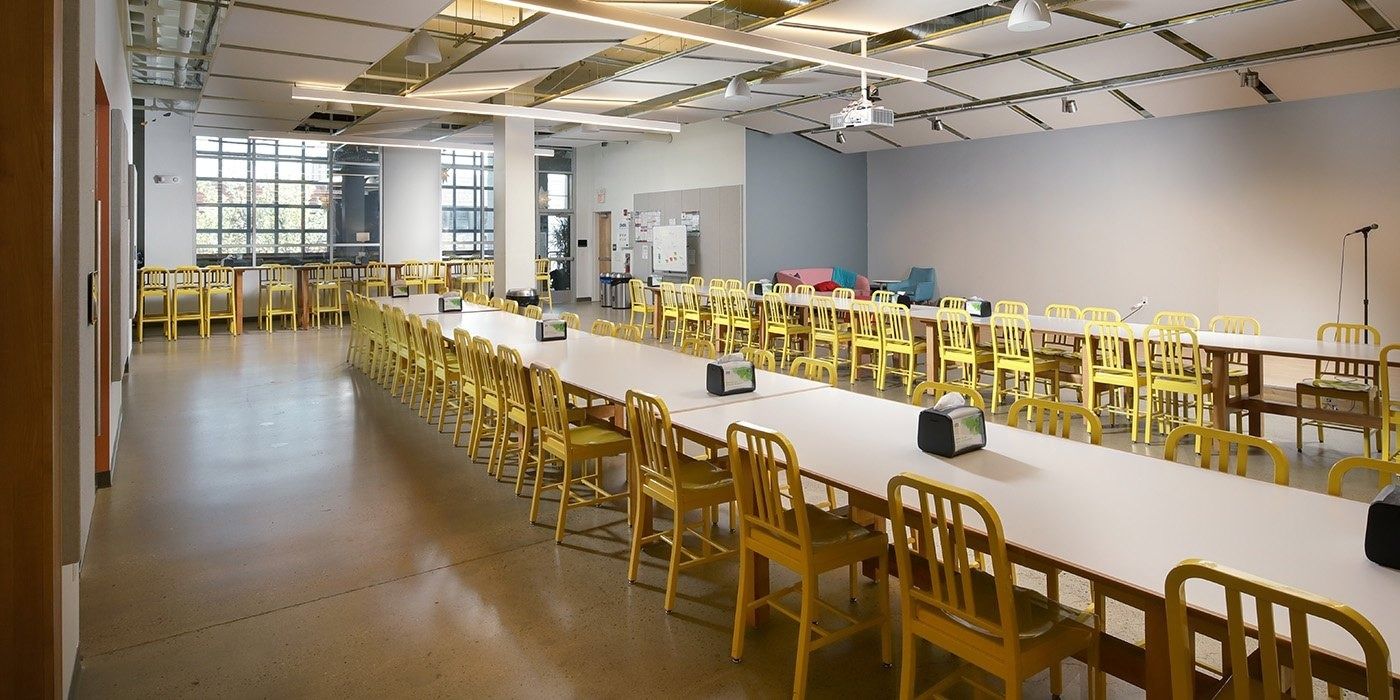 Duolingo: Long white dining tables lined with yellow chairs