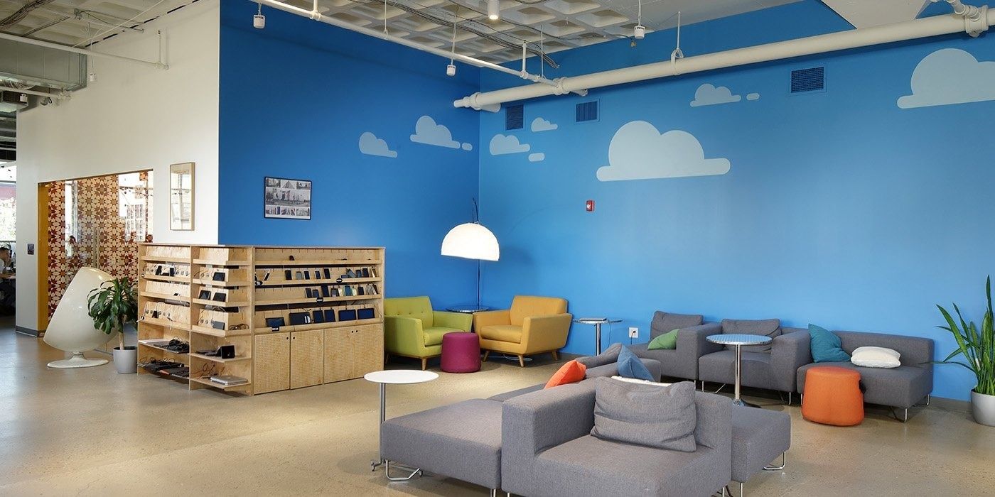 Duolingo: Lounge in front of a blue wall painted with clouds, with gray sofas