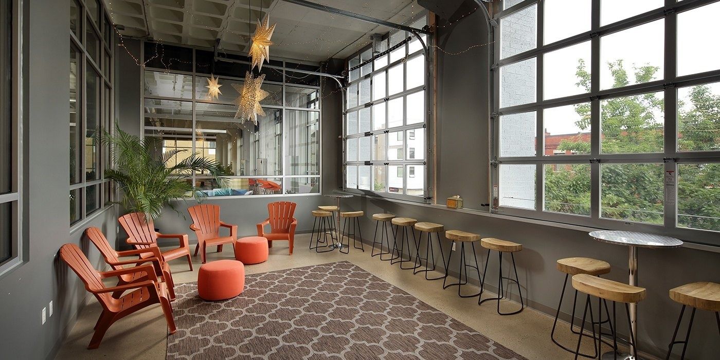 Duolingo: Lounge with orange outdoor chairs, a bar counter and glass garage-style doors