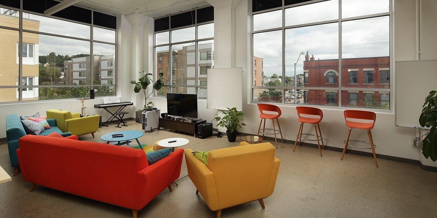 Duolingo: Lounge with red and yellow sofas beside tall windows overlooking brick buildings