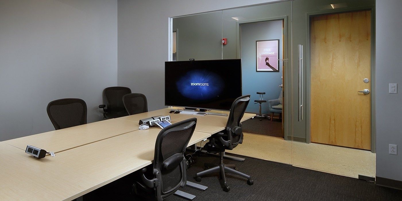 Duolingo: Meeting room with a long white table, office chairs and a wall screen