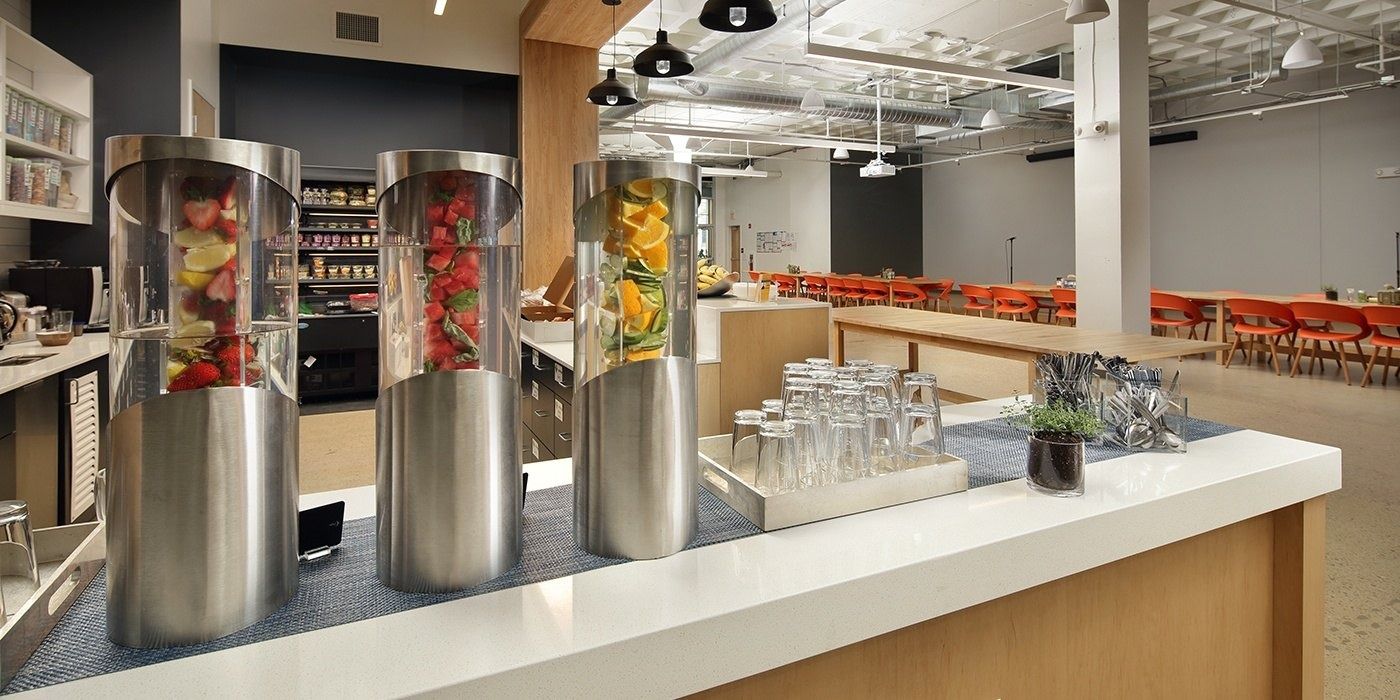 Duolingo: Three tall glass drink dispensers filled with fruit on a white counter