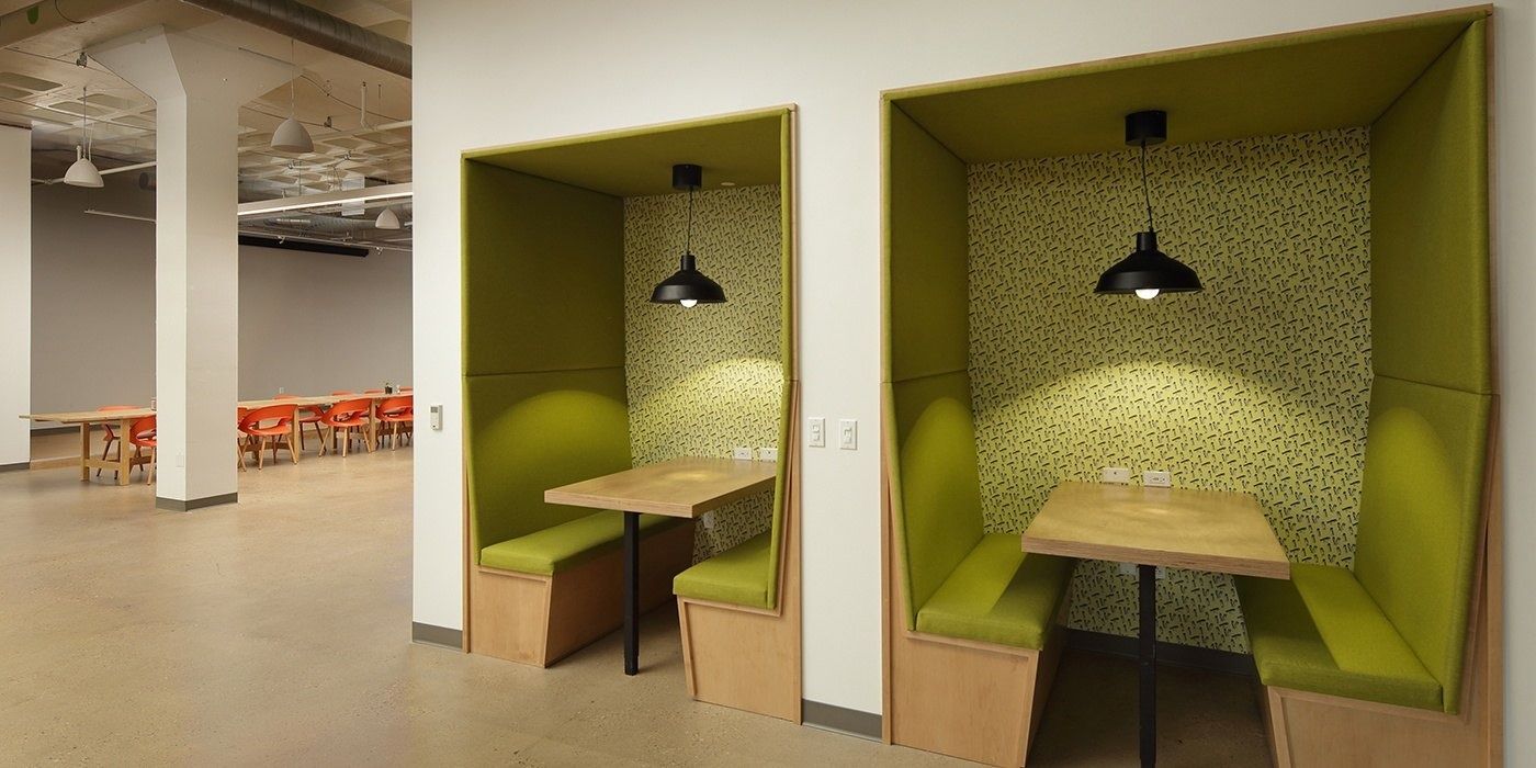 Duolingo: Two green upholstered booths with tables and pendant lamps