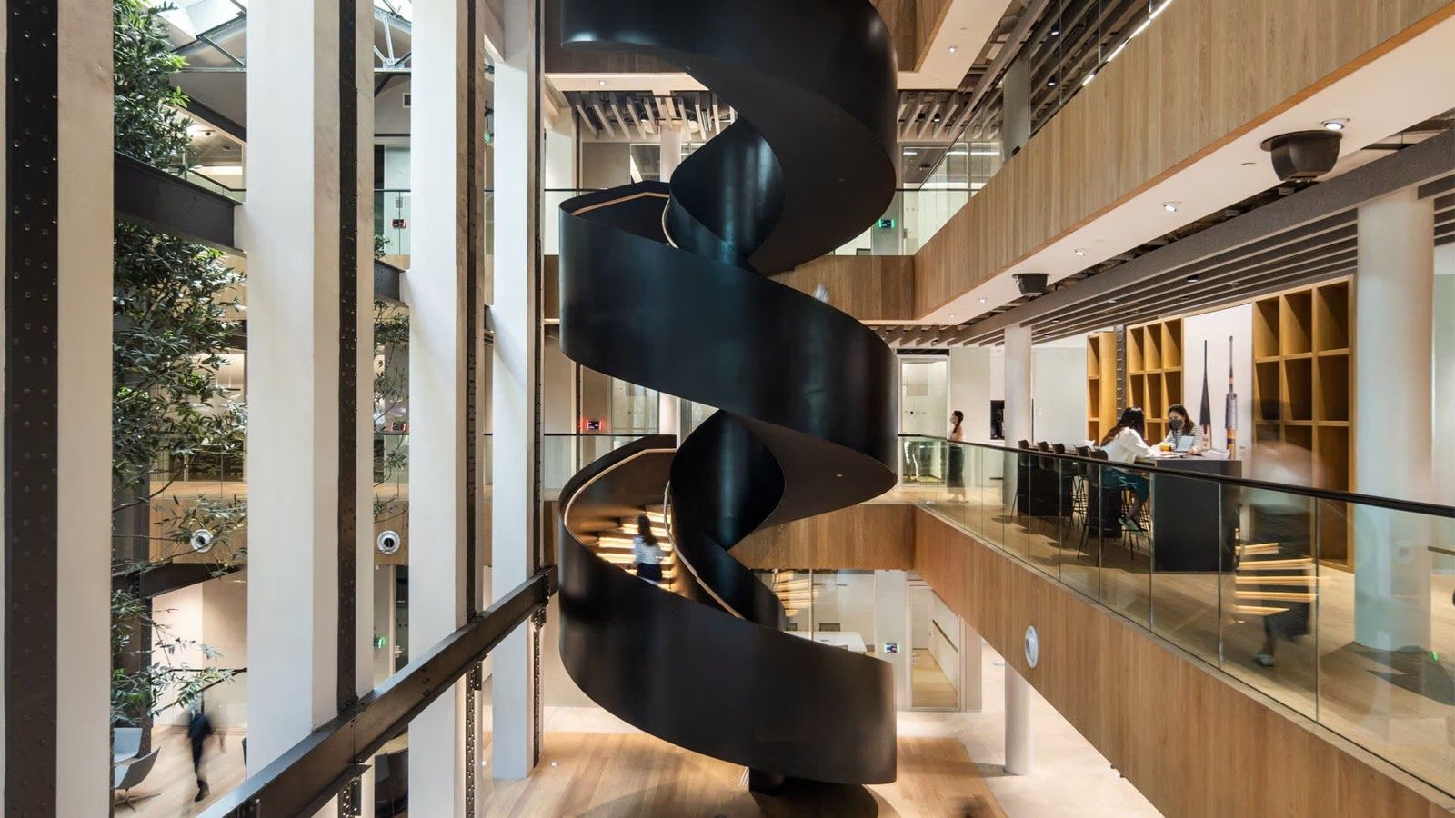 Dyson: Black free-standing spiral staircase rising between timber-clad galleries