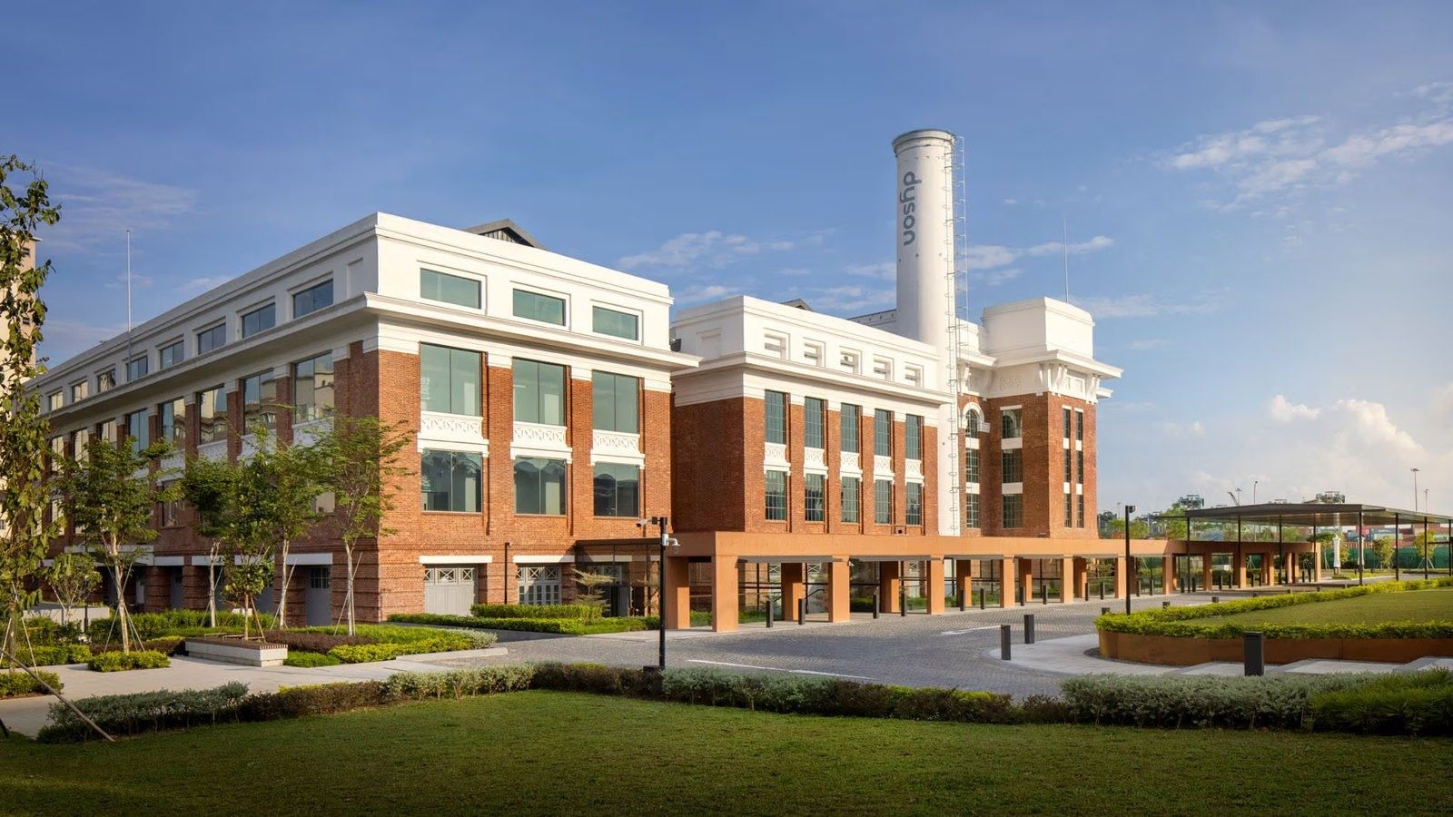 Dyson: Red-brick building with white upper storeys and a white chimney under a blue sky, with a lawn in front