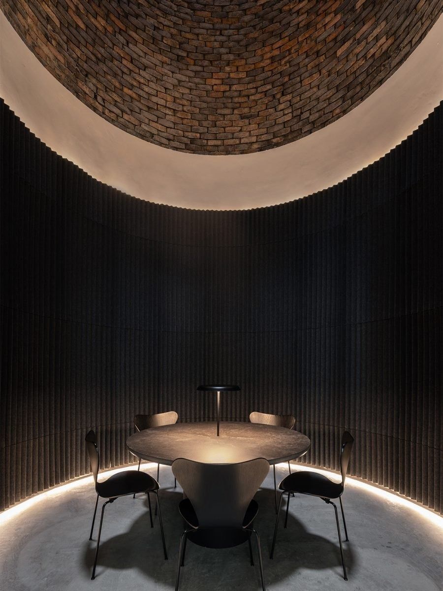 Dyson: Round dark room with a circular table and a brick vaulted ceiling