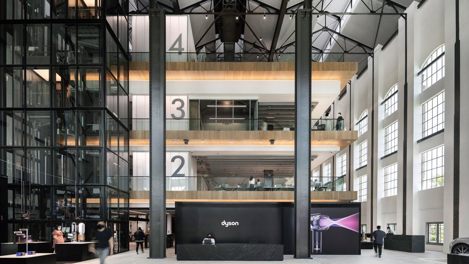 Dyson: Tall industrial hall with steel columns, numbered floors 2 to 4 and a black reception desk at ground level