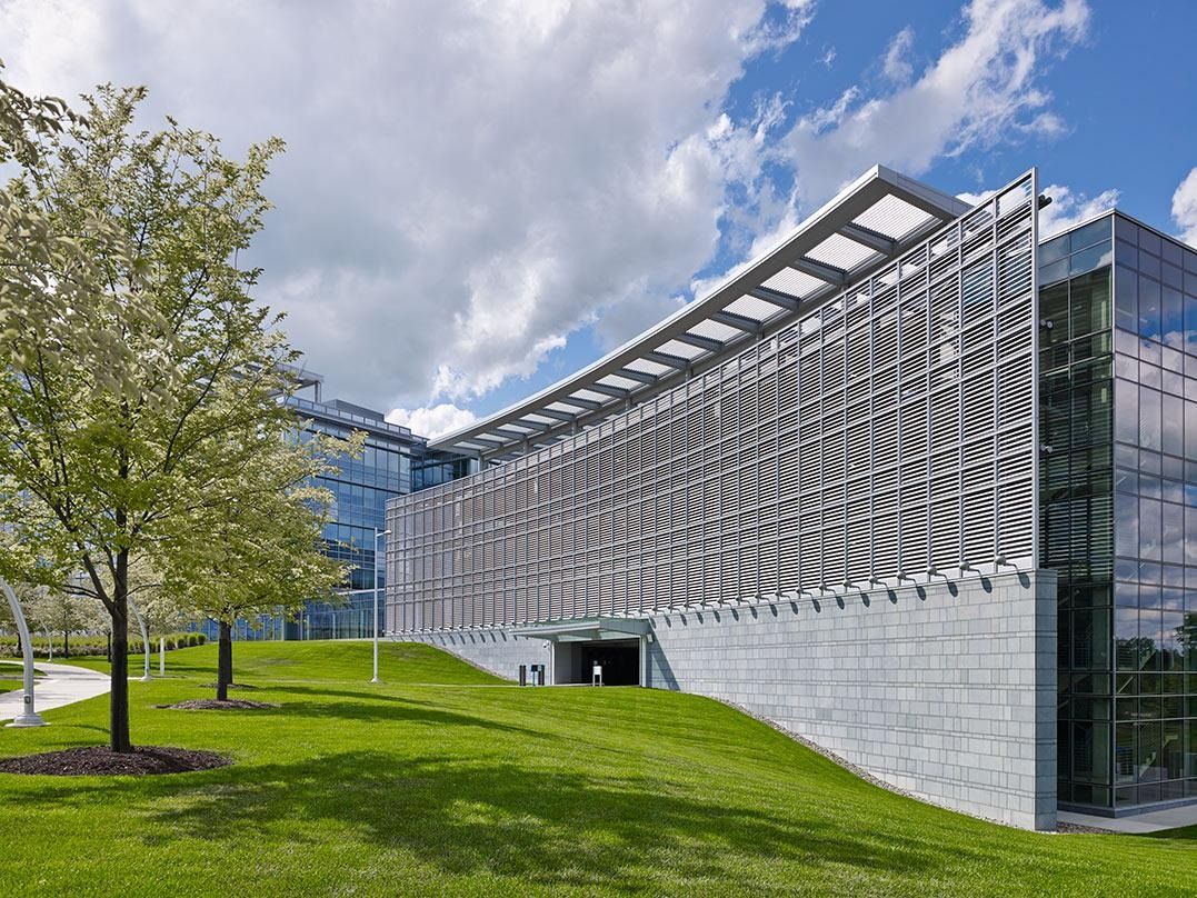 Eaton: A long curving glass wing with a metal sunshade above a grass slope