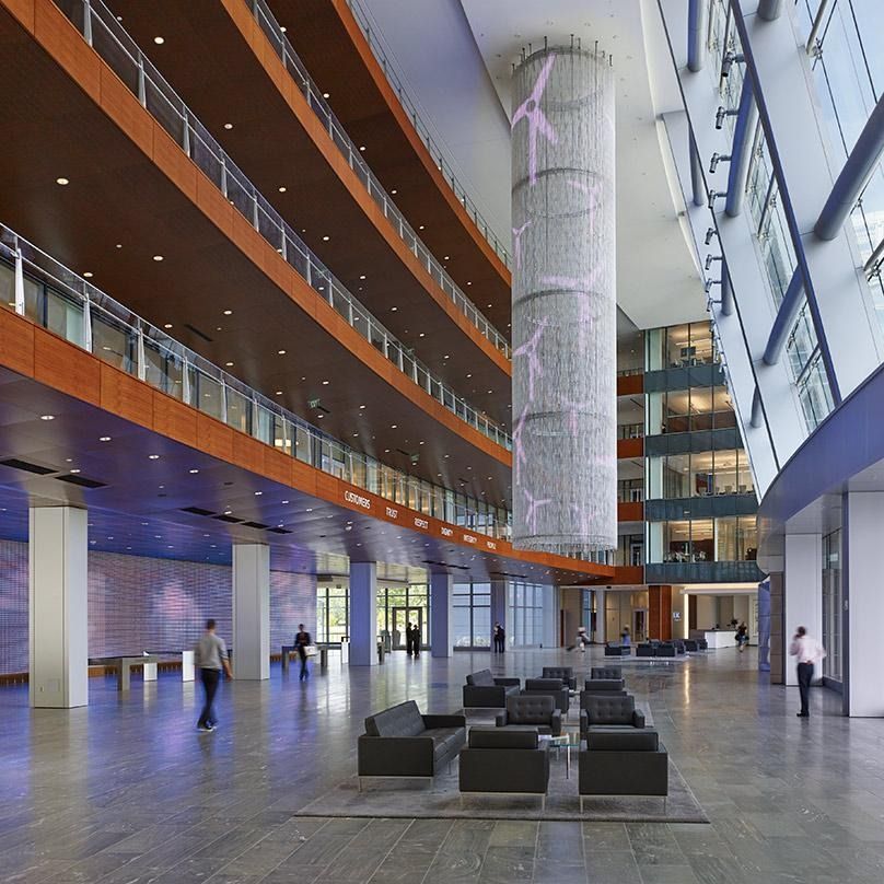 Eaton: A tall atrium with a glass column, wood balconies and lounge chairs