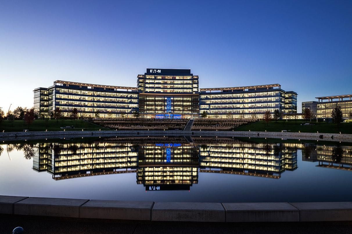 Eaton: Two curved office wings and a central tower reflected in a pond at night